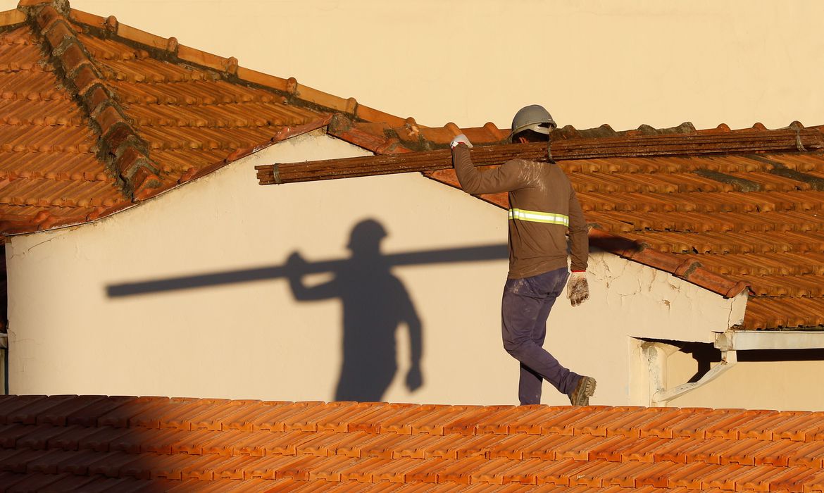 Trabalhadores da construção civil, operários reformam telhado de imóvel em obras no Centro do Rio.