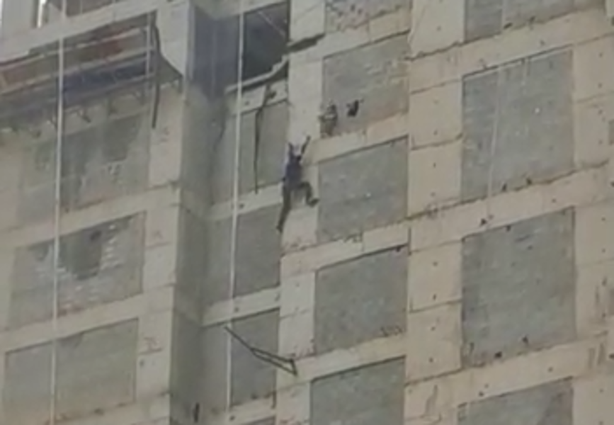 Homem pendurado em prédio em obras em Guarujá