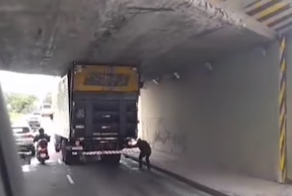 Caminhão fica preso debaixo de viaduto e pneus do veículo precisam ser esvaziados