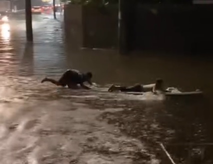 Moradores surfam em rua alagada pelas chuvas em Itanhaém; VÍDEO