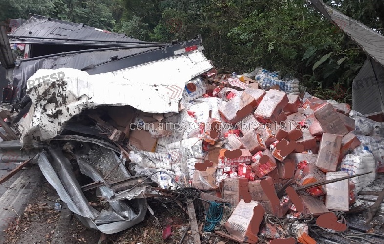Motorista fica ferido após caminhão tombar e carga é derramada na Mogi-Bertioga